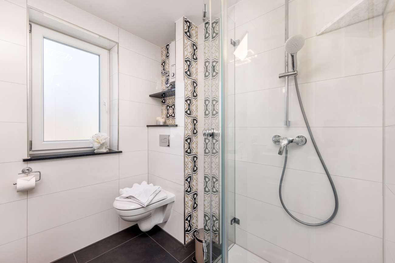 Fewo „Rosenwald am Meer“ Haus Meergold in Sassnitz auf der Insel Rügen - 2-Zimmer-Ferienwohnung Rosen am Meer - Tageslichtbad modern mit Musterfliesen und Glasdusche und Handtuchtrockner